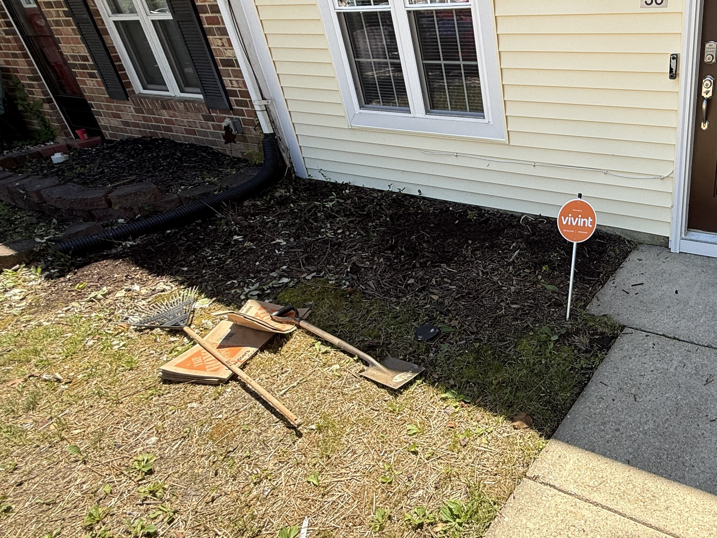 Front bed before landscaping — old mulch and tools on ground